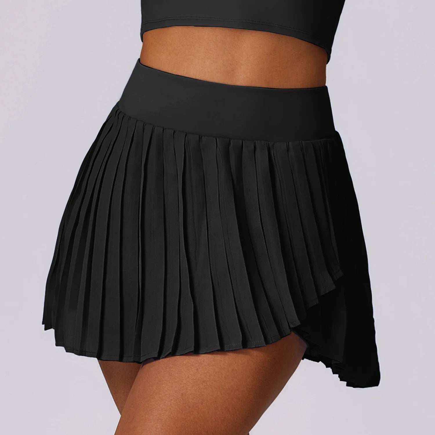 Black pleated athletic tennis skirt on a woman against a light background