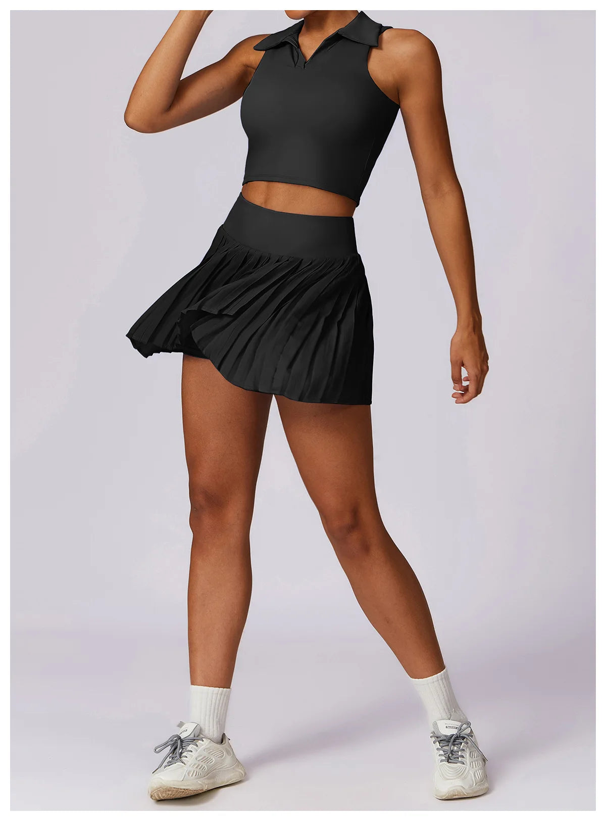 Woman in black sleeveless tennis crop top and pleated skirt activewear set with sneakers