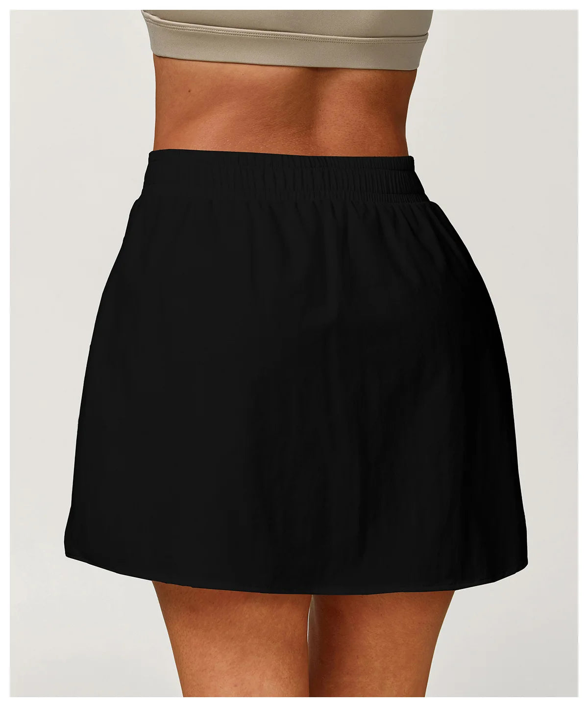 Black high-waisted athletic skirt on model, neutral background, workout fashion