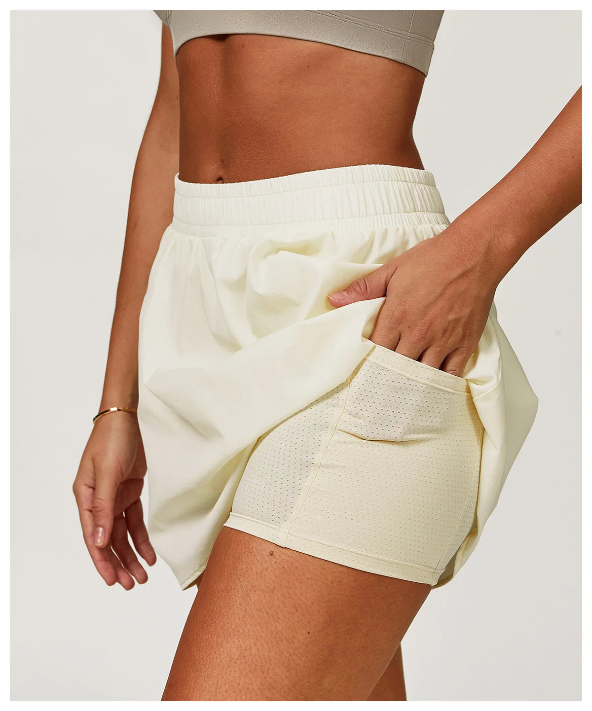 Woman wearing cream athletic shorts with inner mesh liner and pocket, activewear detail
