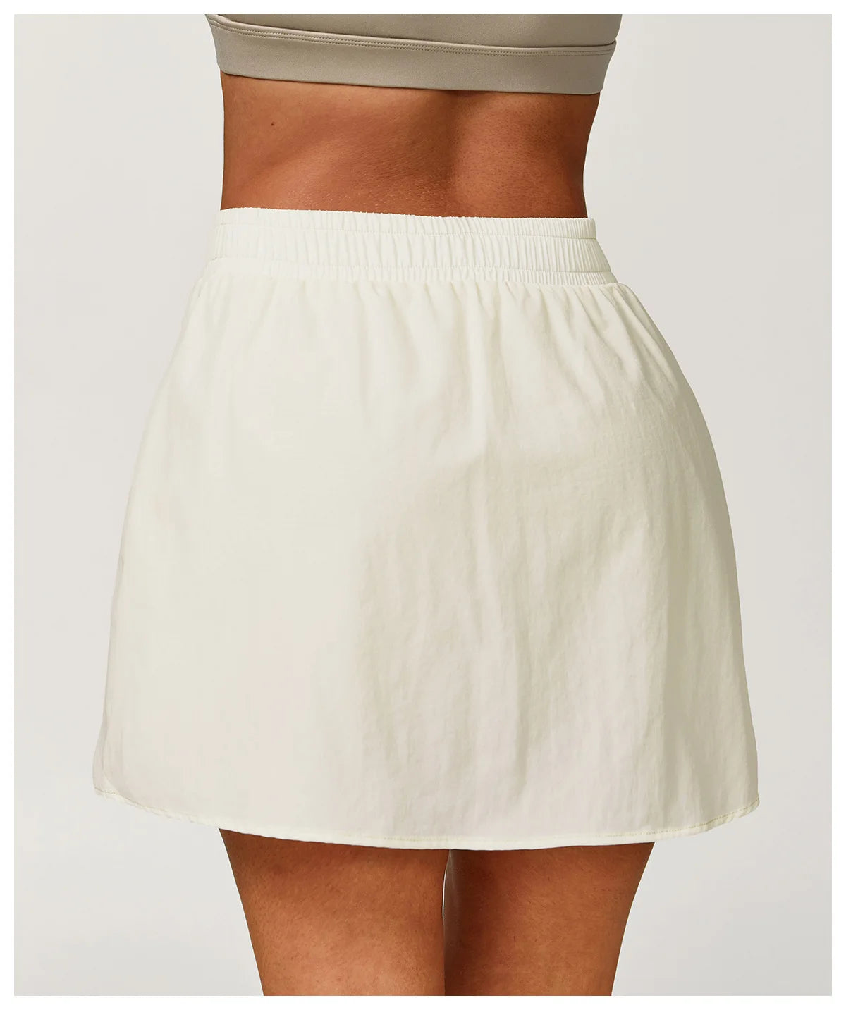 Woman wearing white athletic skirt with elastic waistband, neutral background