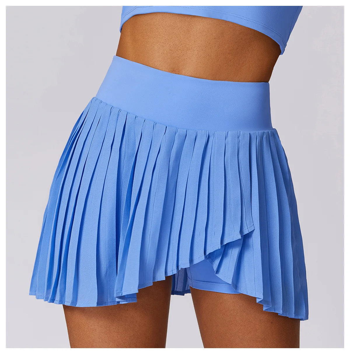 Woman wearing high-waisted pleated blue tennis skirt with built-in shorts