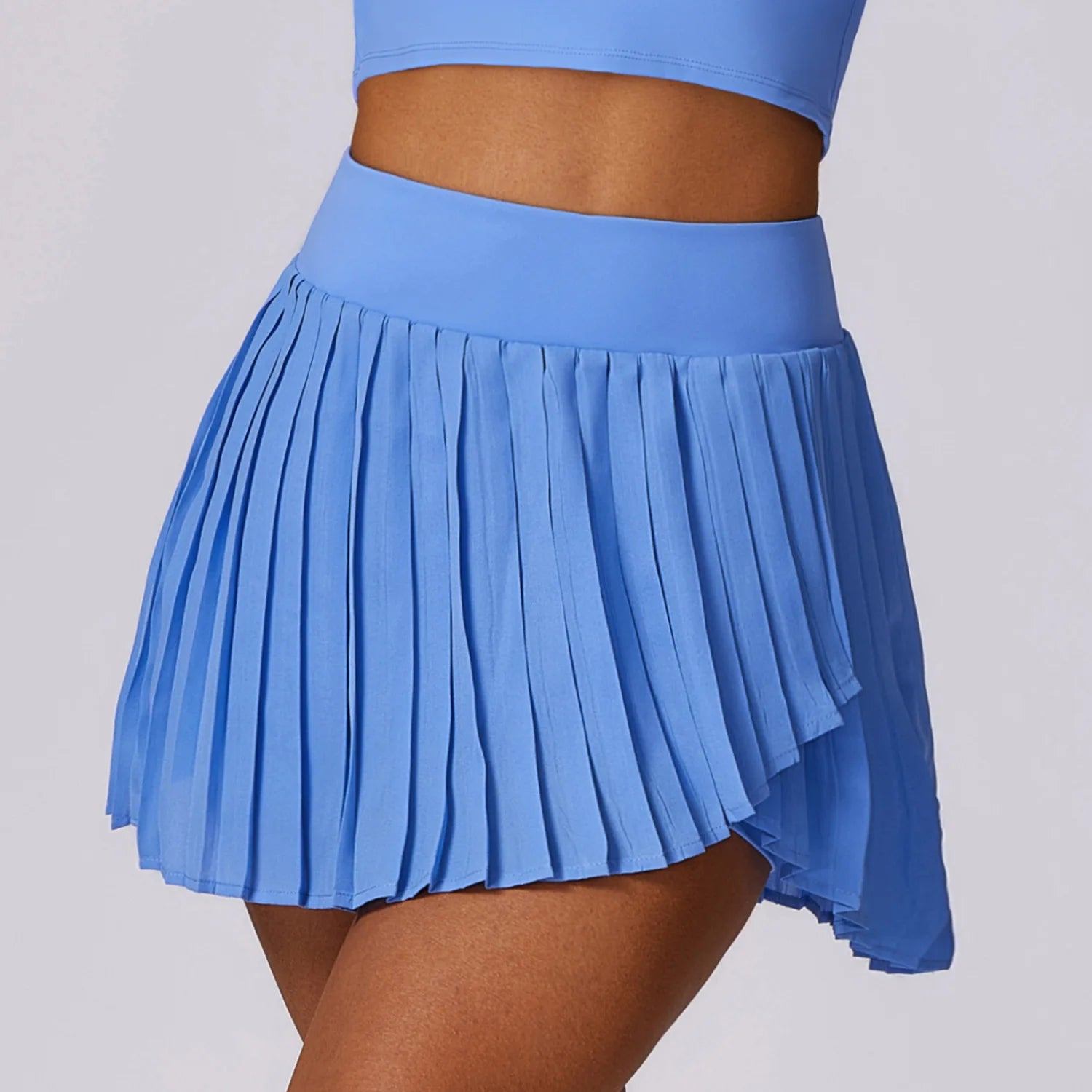 Woman wearing a high-waisted light blue pleated tennis skirt