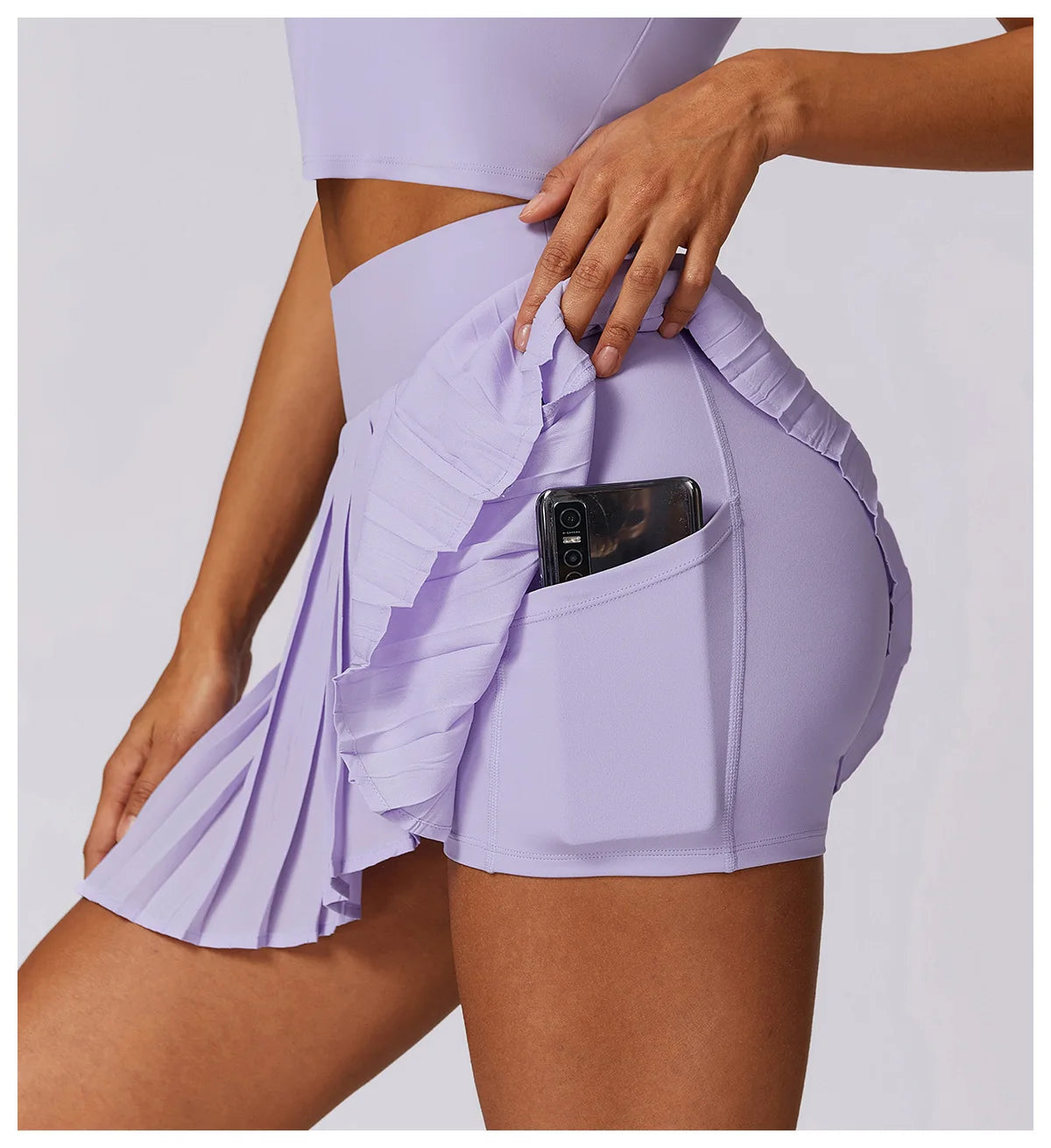 Lilac pleated tennis skirt with side pocket holding a phone, athletic activewear fashion