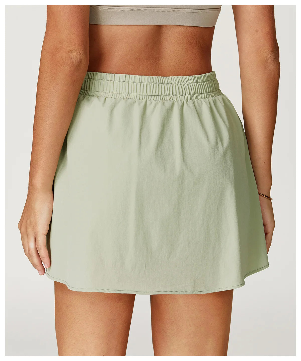 Back view of woman wearing light green athletic skirt with elastic waistband