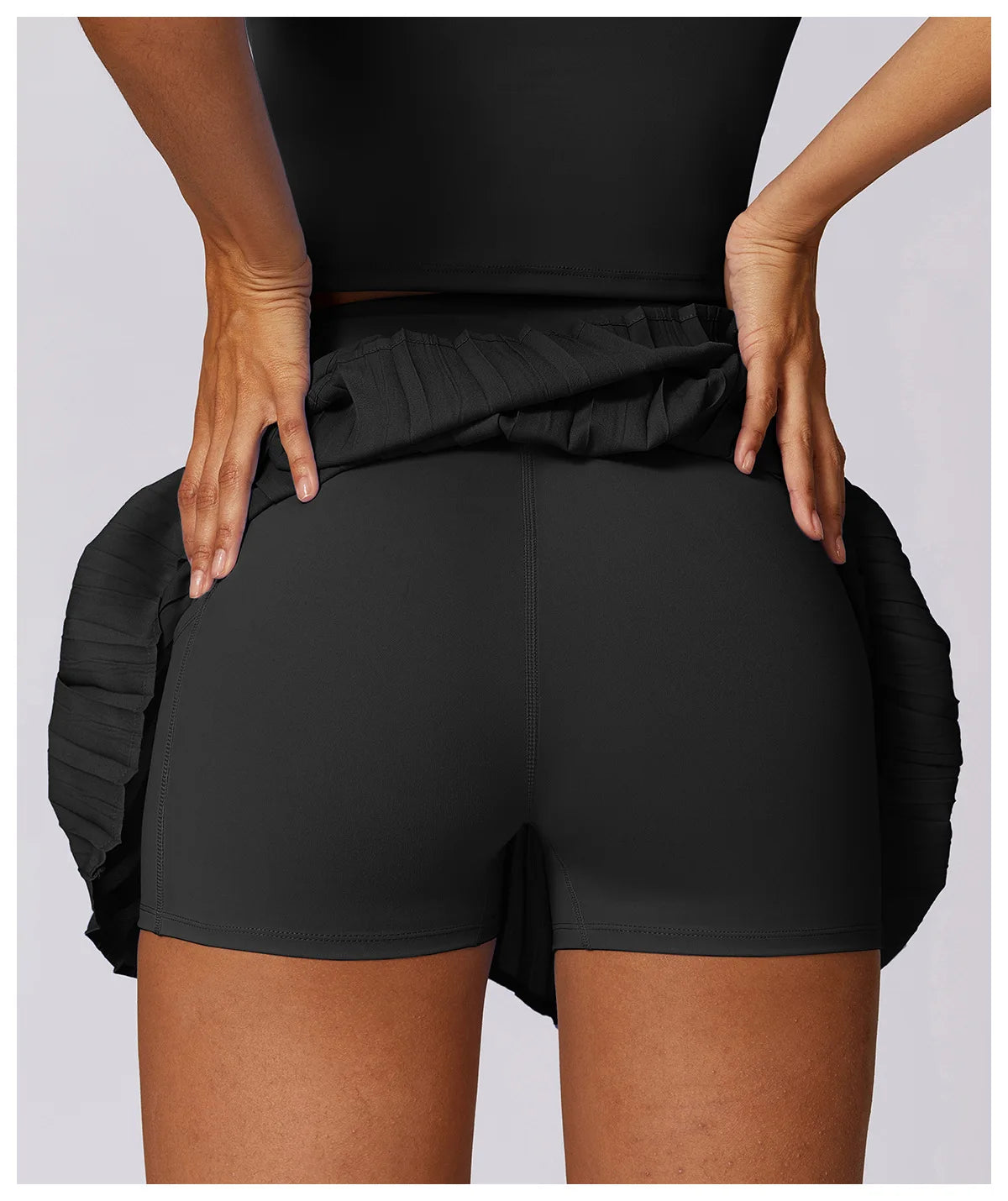 Back view of woman in black high-waisted athletic shorts with pleated waistband detail