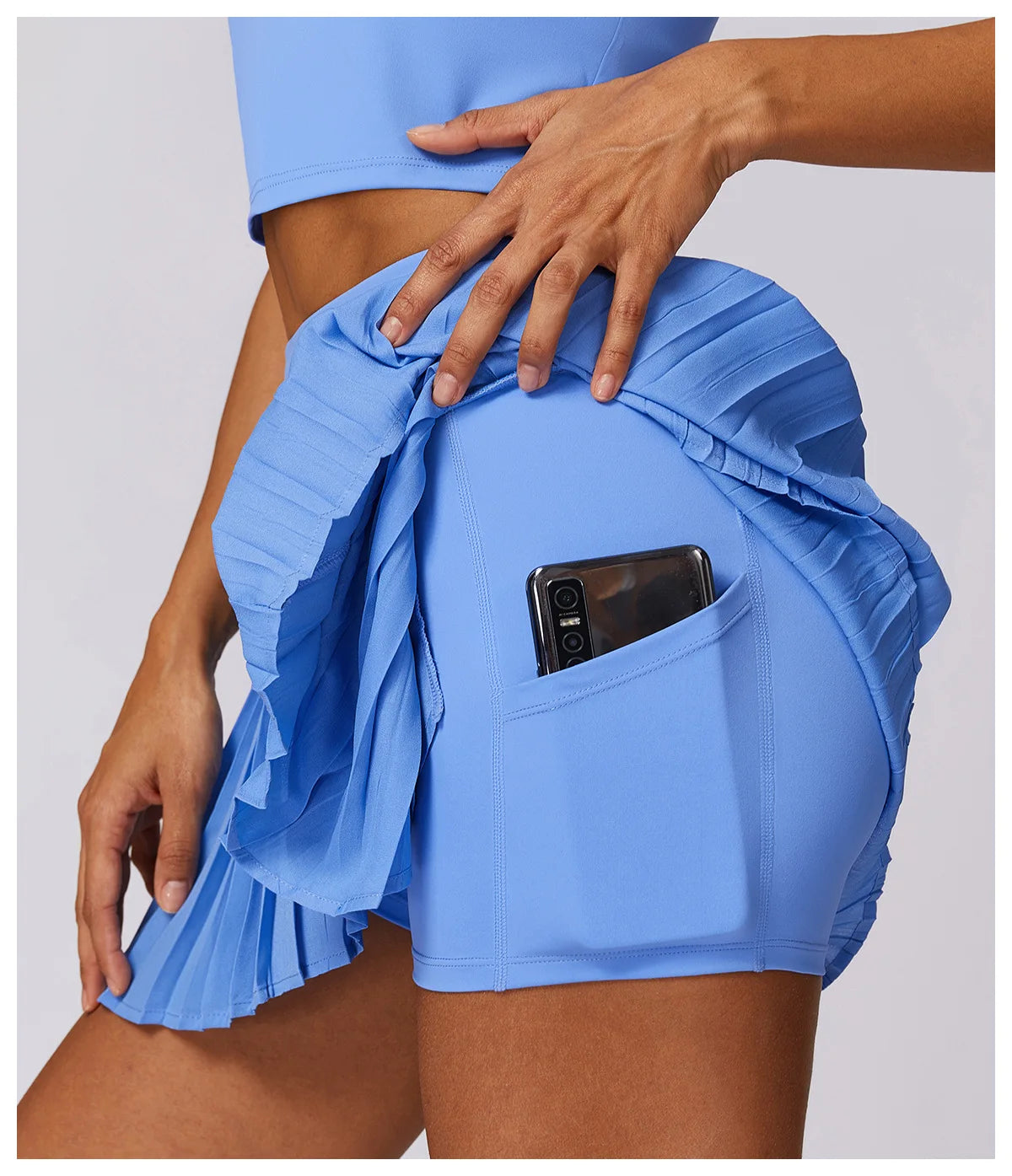 Light blue pleated tennis skirt with shorts and phone pocket, close-up view