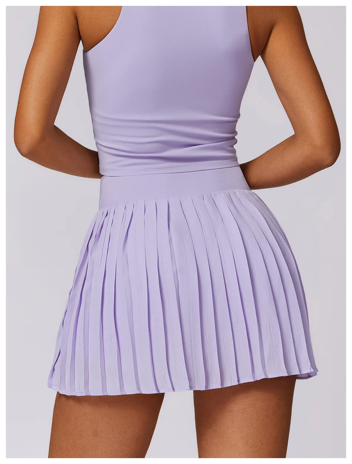 Woman wearing lilac pleated mini skirt and tank top, back view, fashion apparel
